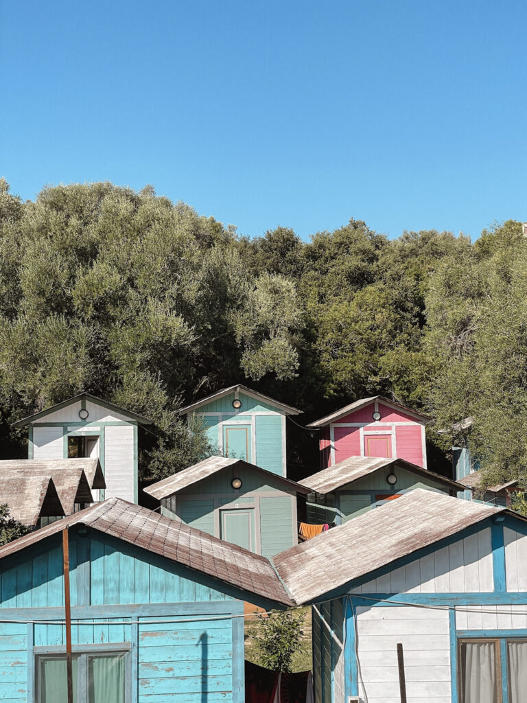 Charming, colorful houses at Jala Beach in Albania with turquoise waters and sunny skies, highlighting why Albania is worth visiting for its picturesque coastal scenery.