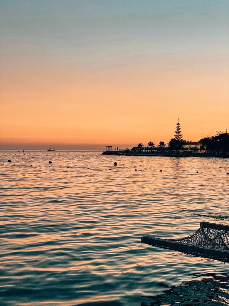 Summer view of Saranda with turquoise water, beach umbrellas, and a lively waterfront, illustrating everyday coastal life when asking Is Albania Safe to Visit.