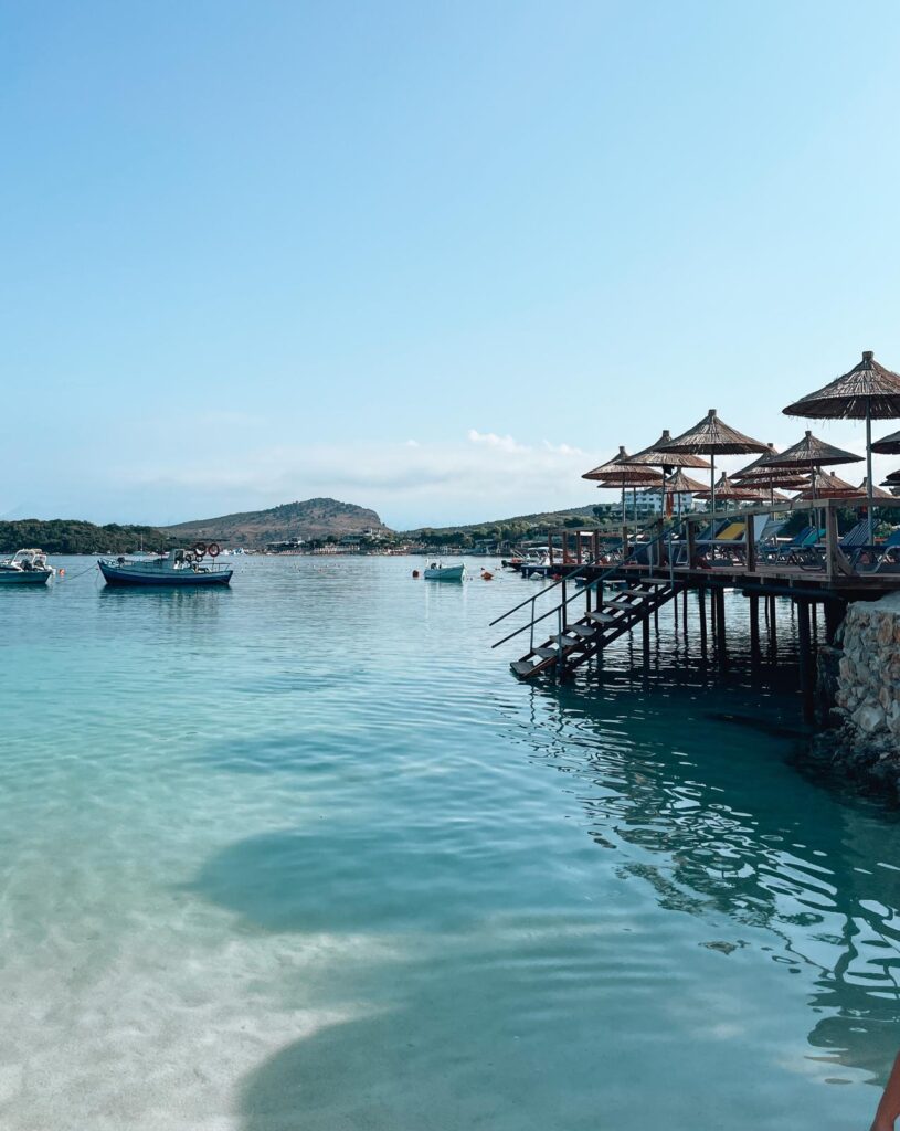 Turquoise water and small sandy beaches at Ksamil with several tiny islands just offshore and sun umbrellas along the shore. The clear Ionian Sea and relaxed beach setting show why coastal destinations are part of the appeal when asking if Albania is a cheap country to visit.