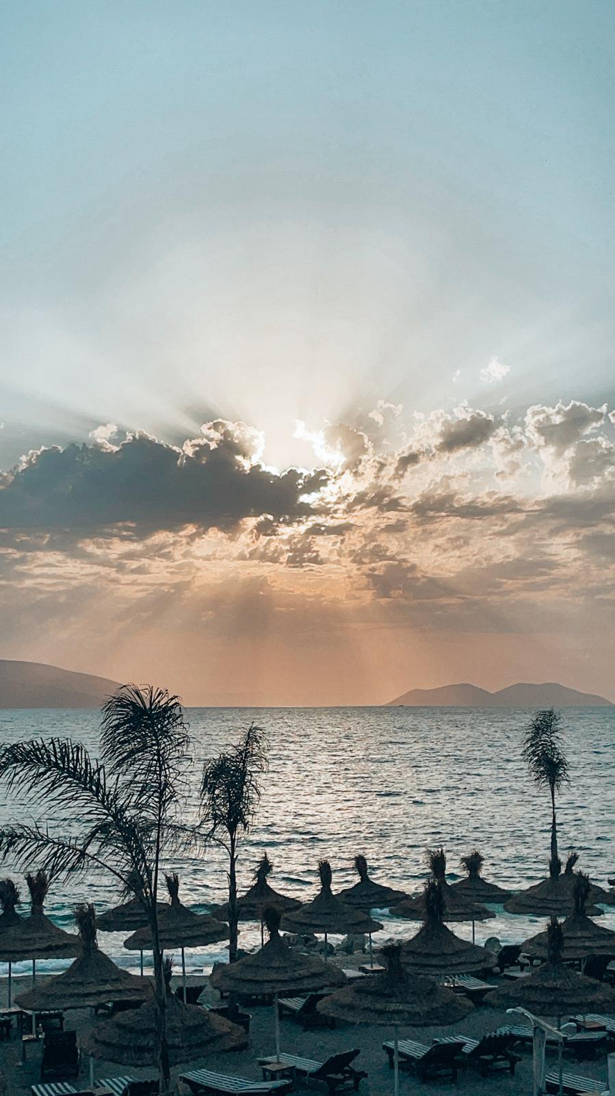 Warm sunset over Vlorë as the sun dips into the Ionian Sea with orange and pink sky reflecting on the water during a relaxed evening along the Albanian Riviera where travelers often compare everyday costs such as supermarket prices in Albania.