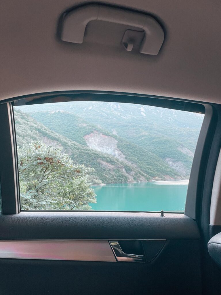 Car driving along a scenic coastal highway in Albania with sweeping sea views and mountain curves, reflecting the road trip experience that often begins with the corfu to saranda ferry.
