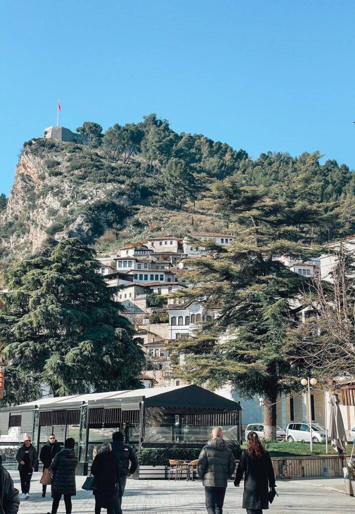 Panoramic view of Berat, Albania, showing white Ottoman-style houses stacked on hillsides and the Osum River winding below under a soft sunlight. This historic town is a picturesque and Instagrammable spot in Albania.