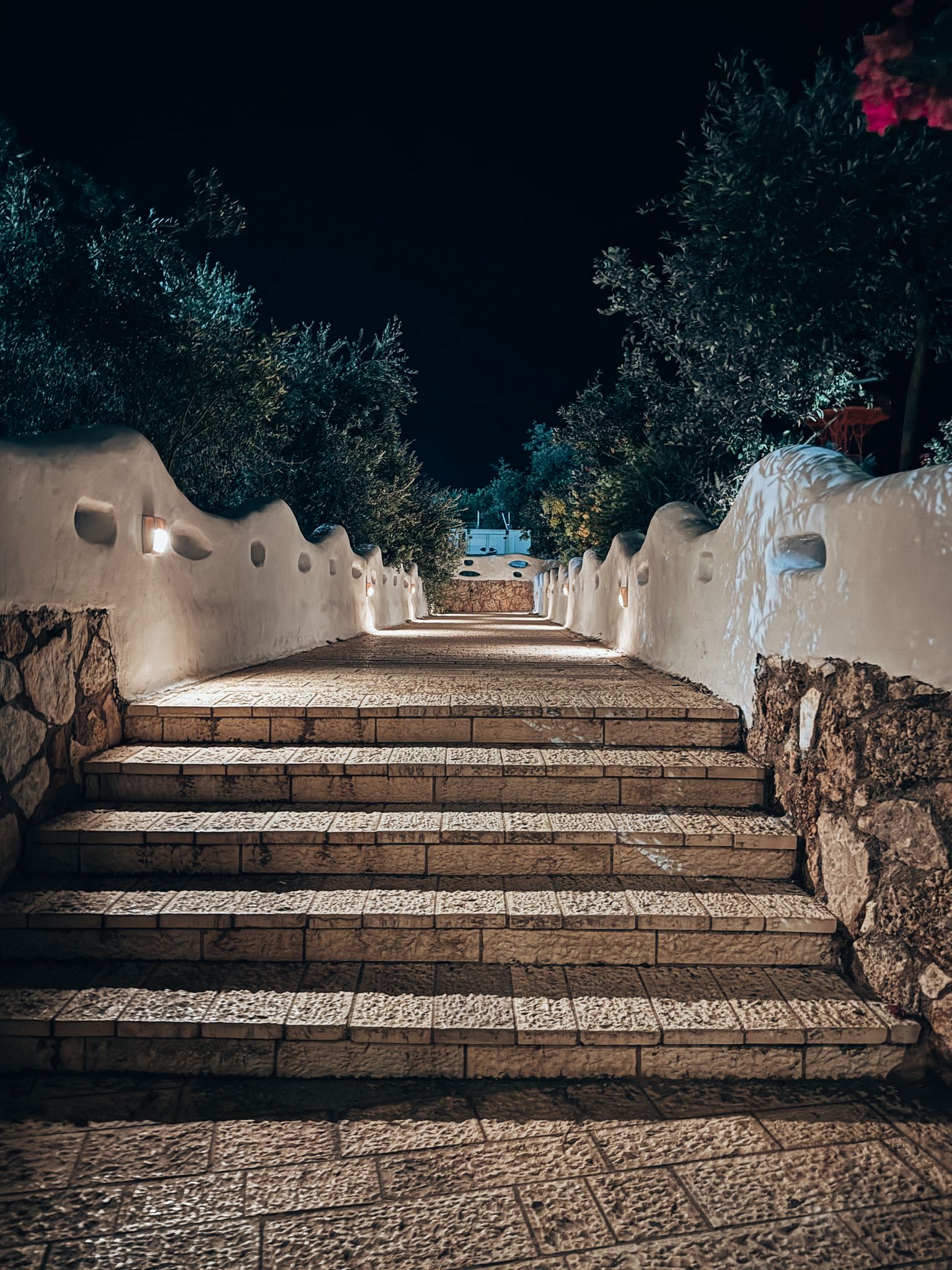 Exterior of a restaurant at night with warm lights illuminating outdoor tables and a cozy atmosphere under the dark sky. The inviting evening setting reflects the relaxed nightlife experience while backpacking Albania.