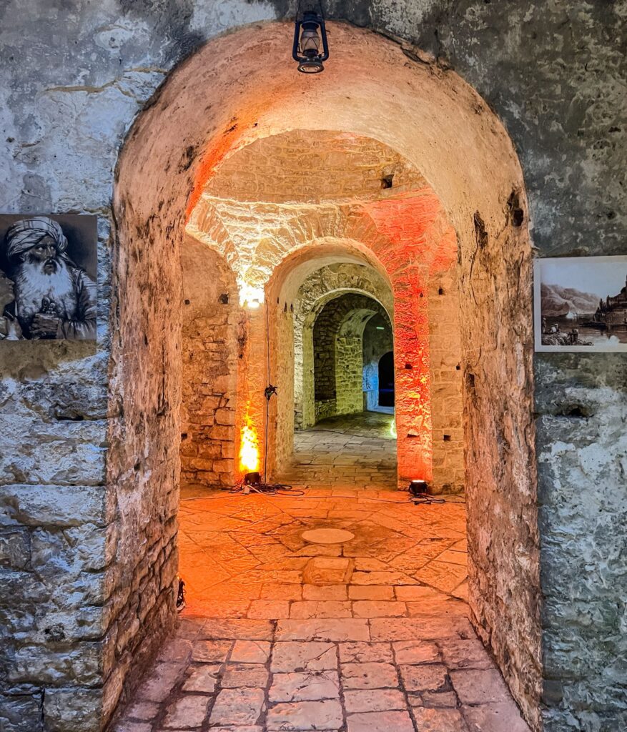 Stone ruins of Ali Pasha Castle perched on a rocky peninsula surrounded by turquoise sea under clear skies. The historic fortress showcases authentic experiences in Albania through its dramatic coastal setting and cultural heritage.