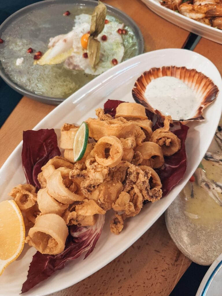 Crispy fried calamari served on a plate with lemon wedges and dipping sauce at Fishop restaurant in Tirana. The golden texture and simple presentation highlight the seafood quality found in the best restaurants in Tirana.