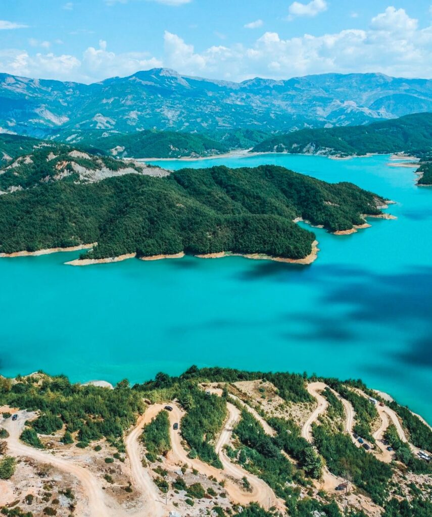 Turquoise Bovilla Lake curves between steep rocky mountains and green hills, a scenic nature spot often included in day trips from Tirana for hiking and views.