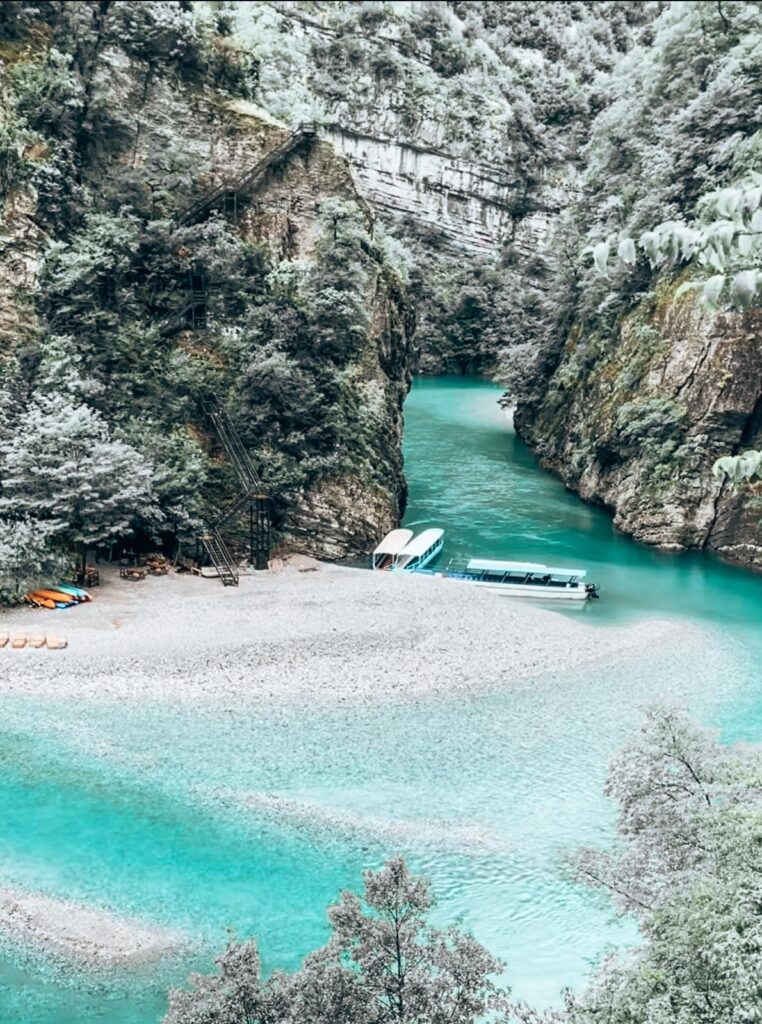 Bright turquoise Shala River flows through steep rocky cliffs and lush greenery, a remote and peaceful destination featured in adventurous day trips from Tirana.