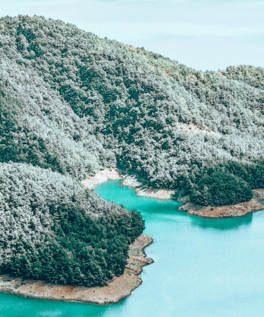 Scenic landscape of Lake Bovilla stretching into the distance with layered mountains fading into a hazy horizon.