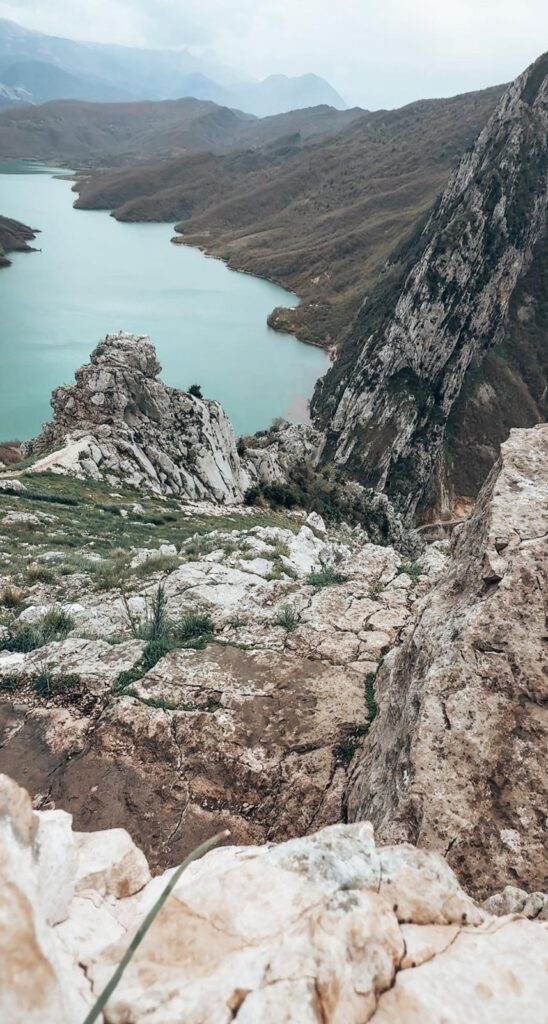 Elevated perspective of Lake Bovilla highlighting the contrast between the vivid water and the dry, rocky terrain around it.