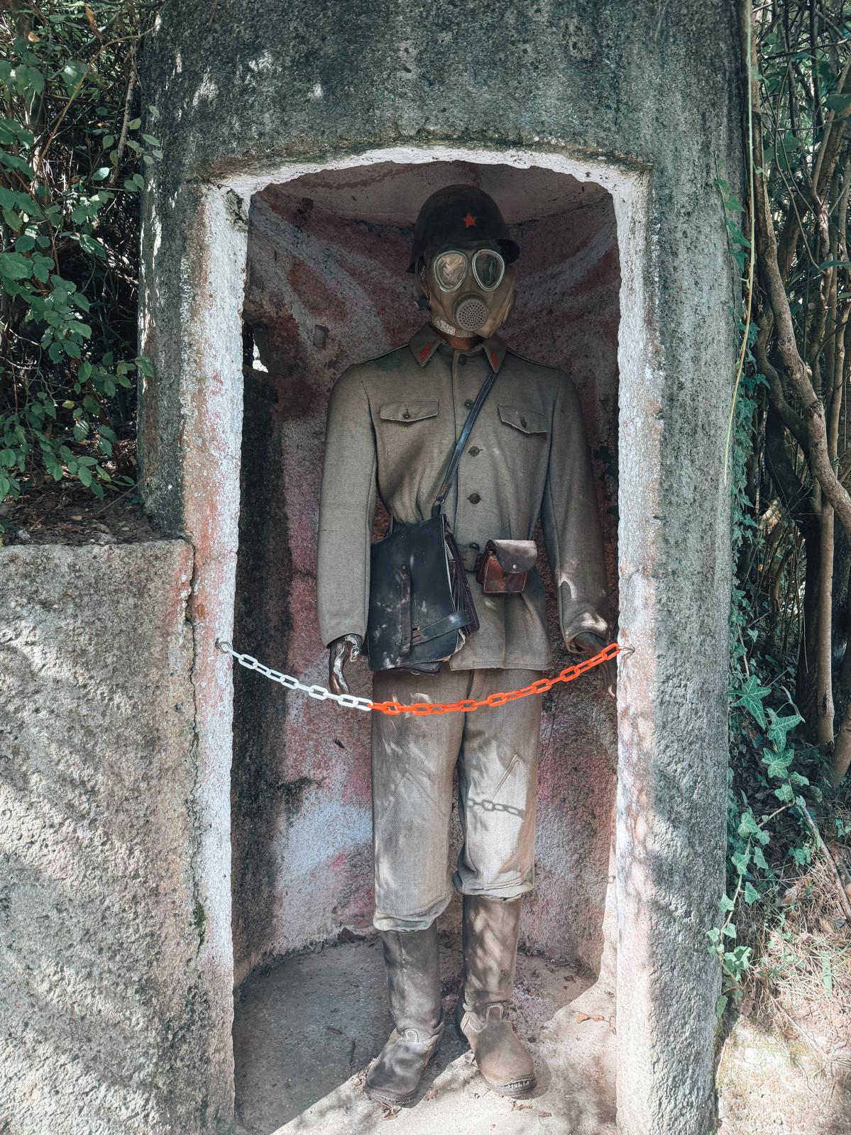 A soldier in uniform stands in a stark setting, representing the military presence during Albania’s communist era. The figure adds context to visiting a bunker in Albania and understanding its defensive purpose.