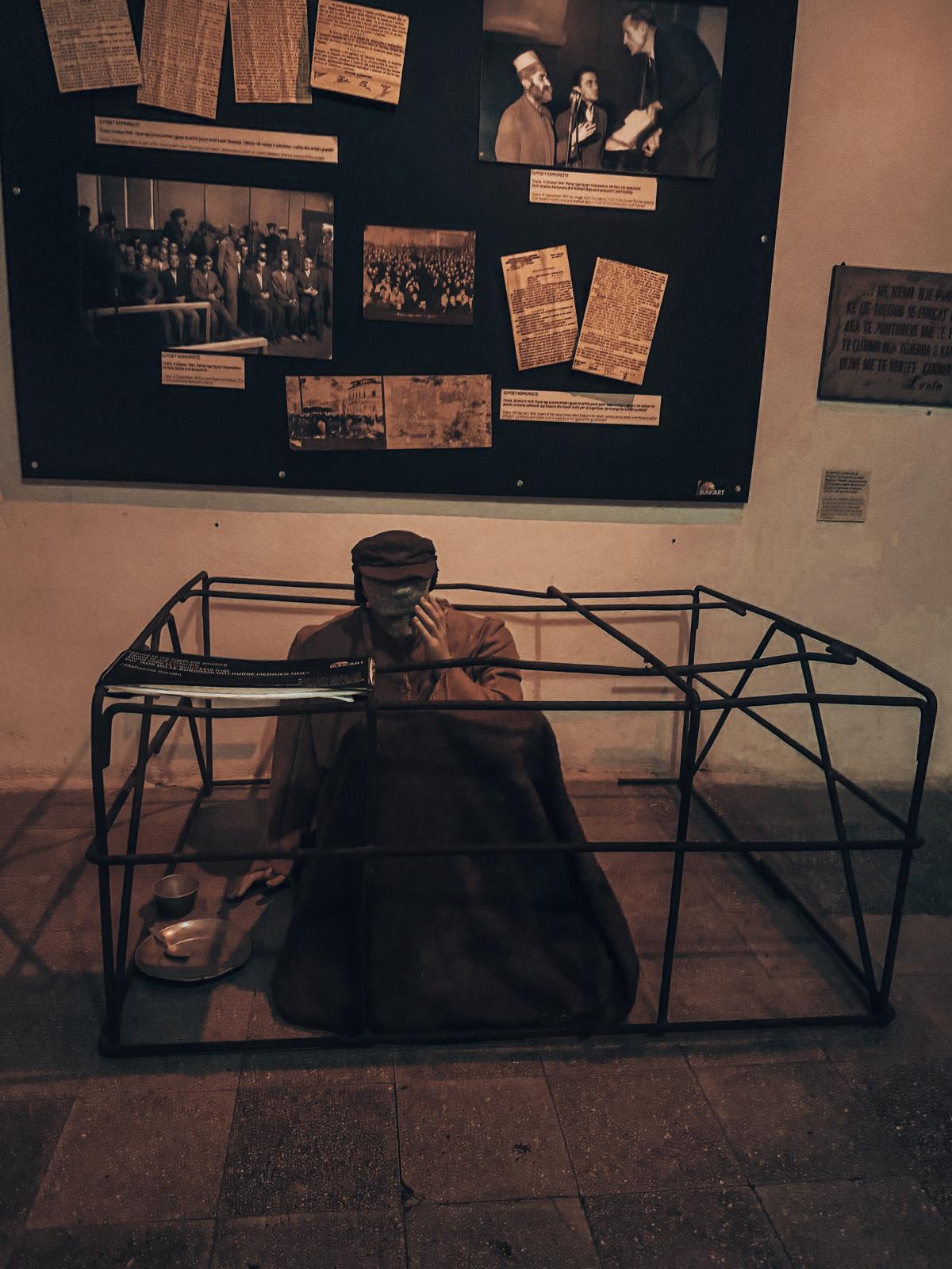 A man during the communist era stands bowed down with a solemn posture, reflecting hardship and control under the regime. The scene adds historical context to visiting a bunker in Albania and understanding life during that period.