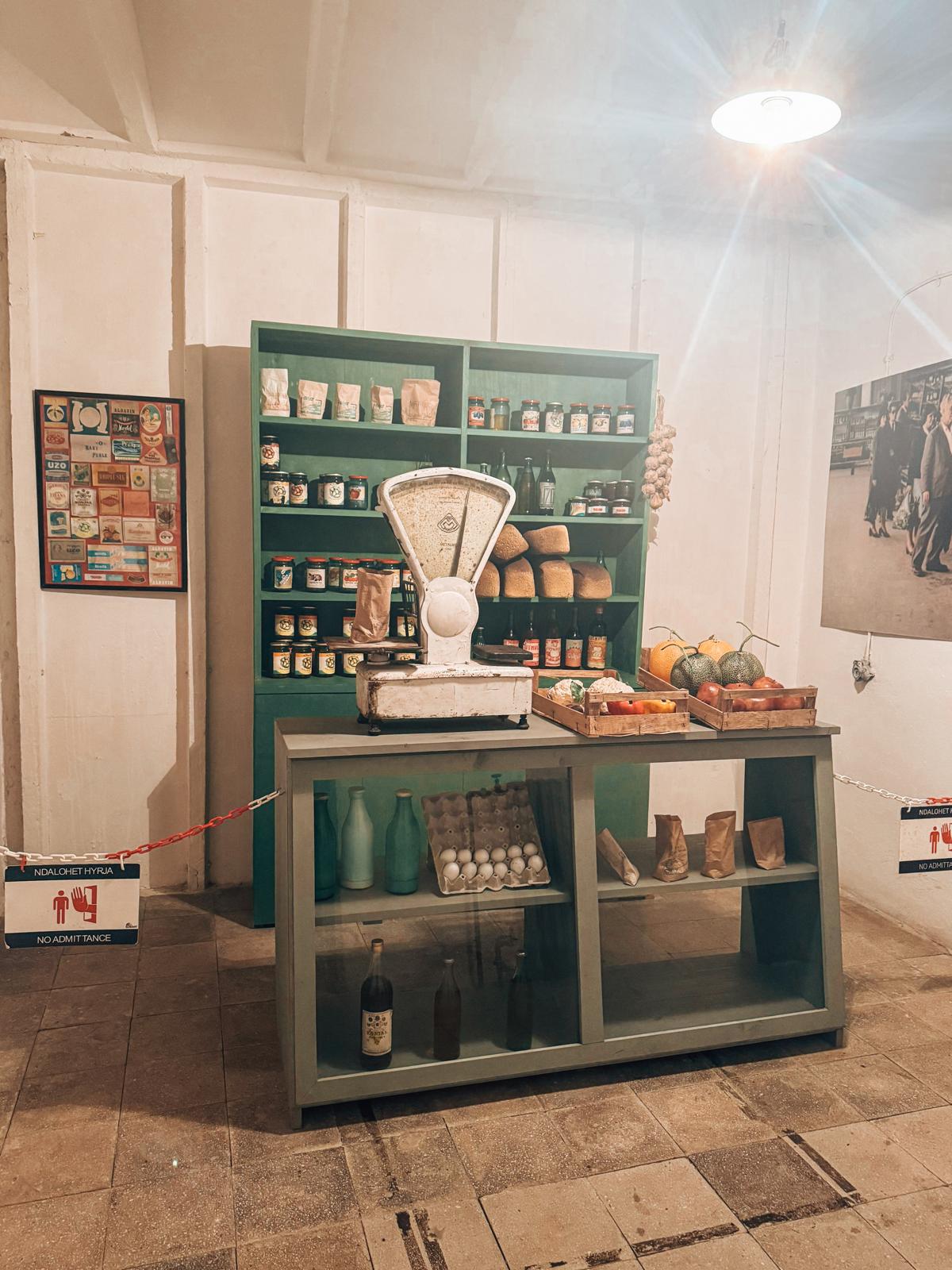 An old market in Albania with a worn metal balance scale surrounded by vintage goods and traditional products on display. The rustic setup gives a glimpse into everyday life and commerce often seen when visiting a bunker in Albania and exploring nearby historic areas.