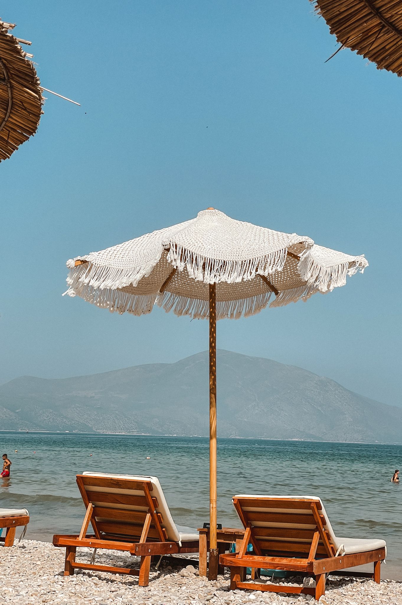 Elevated viewpoint over the Karaburun Peninsula showing dramatic cliffs dropping into deep blue Ionian Sea waters. The sweeping coastal panorama emphasizes the wild, hidden nature of secret beaches in Albania.