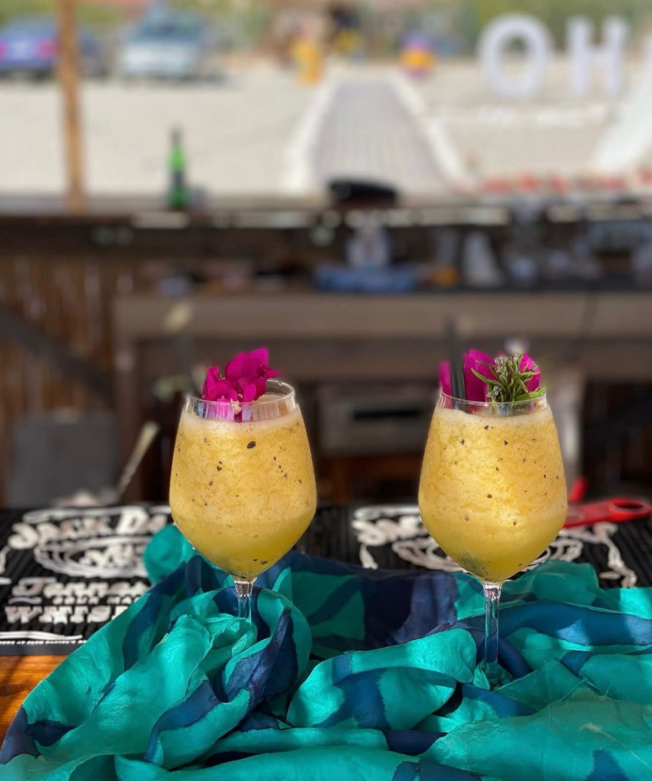 Colorful cocktail glasses arranged on a table at Boho Beach Bar with ocean views and relaxed beach club atmosphere in the background. Fresh garnishes, tropical drinks, and sunset lighting capture the lively vibe of beach bars and clubs in Albania.