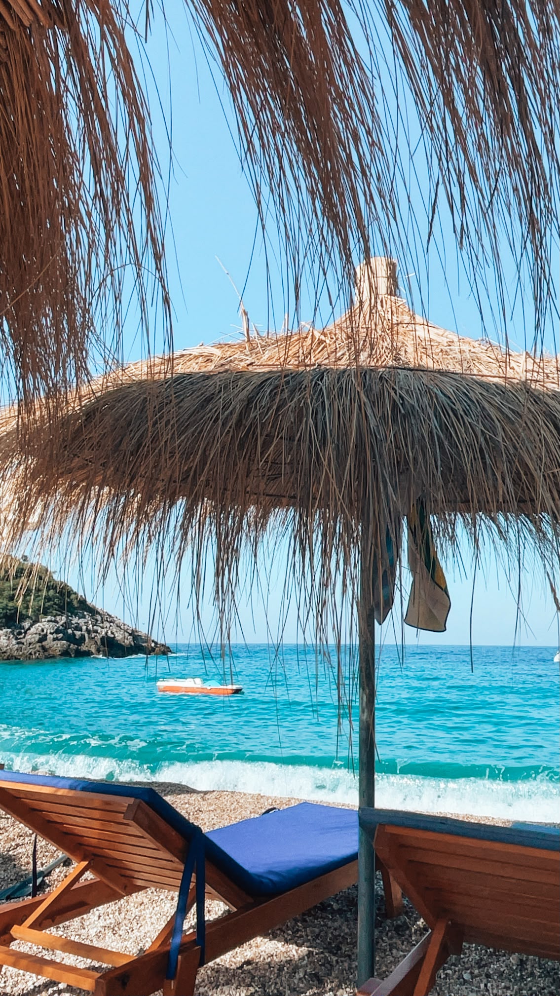 Jala Beach with bright turquoise water, a curved shoreline lined with white pebbles, and boats anchored close to the coast. The lively yet scenic atmosphere captures why it belongs among the Best Beaches in Himare.