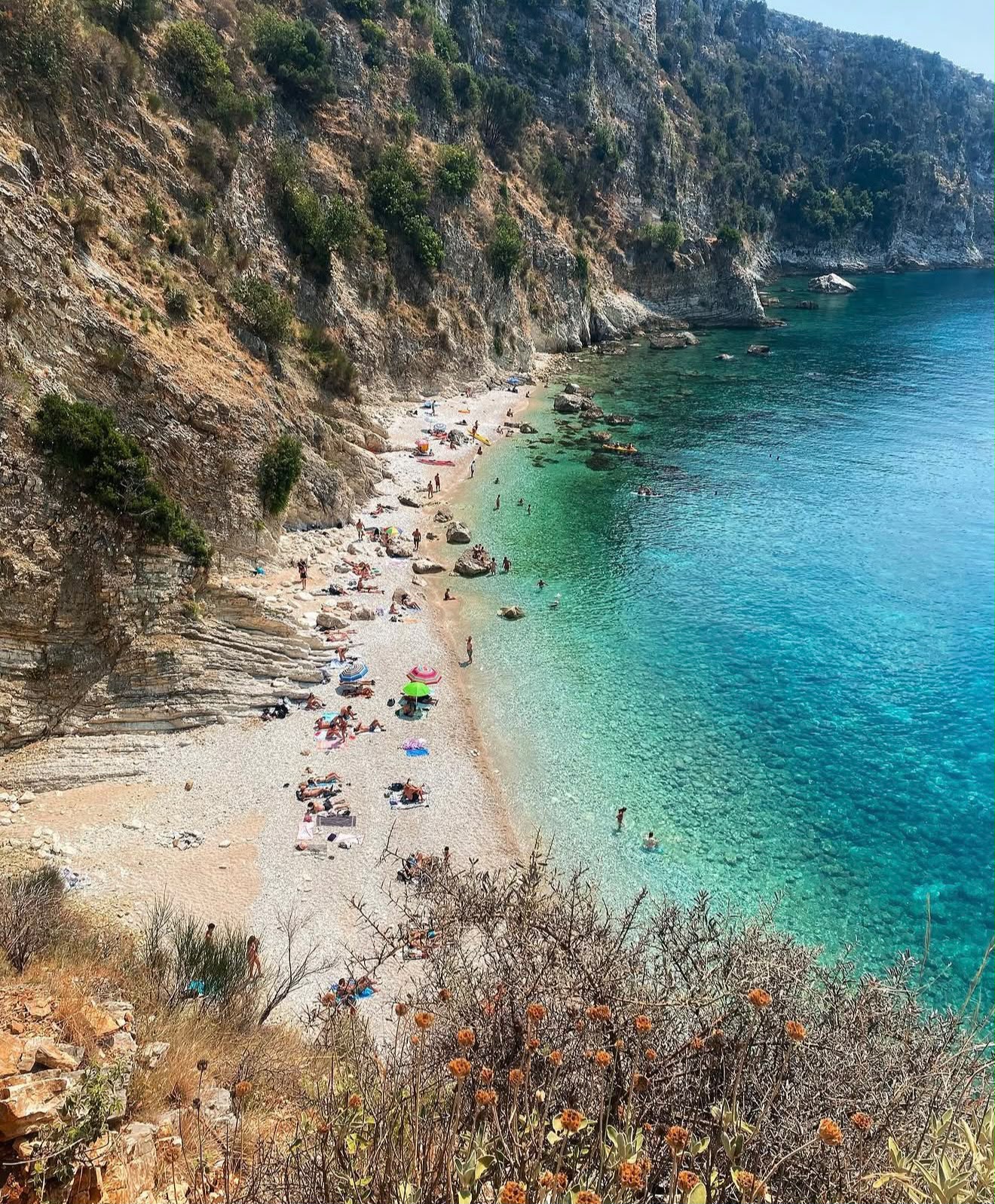 Filikuri Beach in Himarë seen as a hidden rocky cove surrounded by steep cliffs and deep blue water along the Albanian Riviera. This secluded spot is one of the beaches in Himarë reachable by scooter, often viewed from above due to its steep access and dramatic coastal scenery.