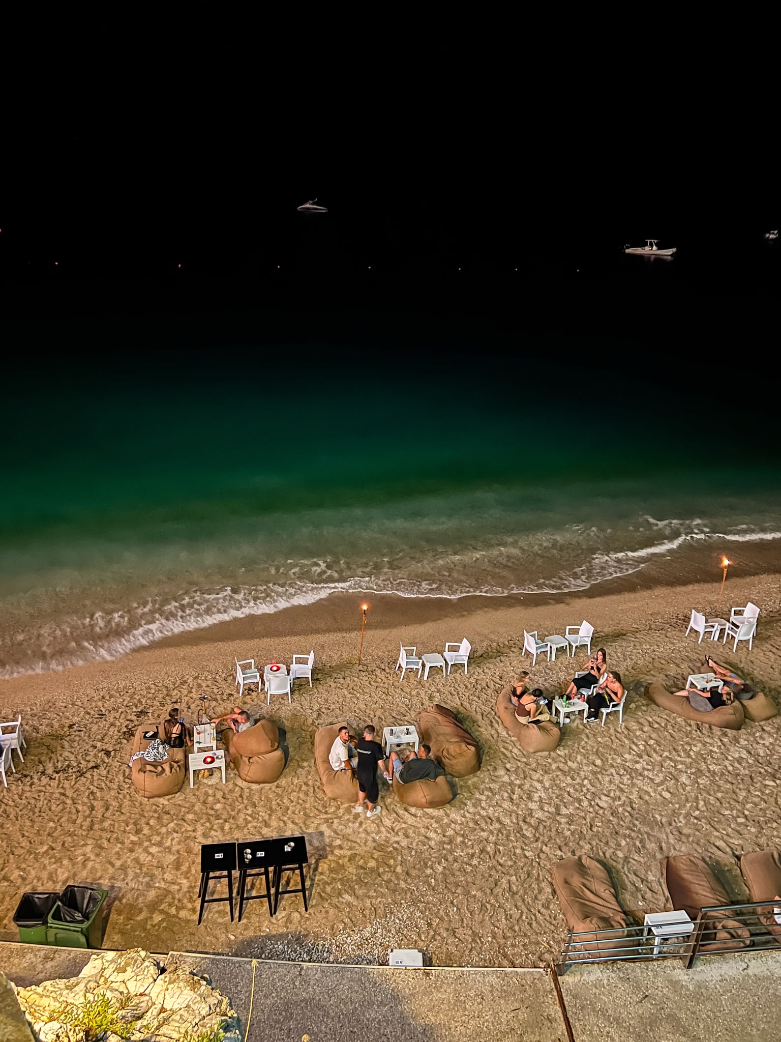 Himarë Beach at night with calm water reflecting lights from the shoreline and nearby buildings. The quiet seaside atmosphere highlights why this stretch of coast is featured among the best quiet beaches near Himarë you can walk to.