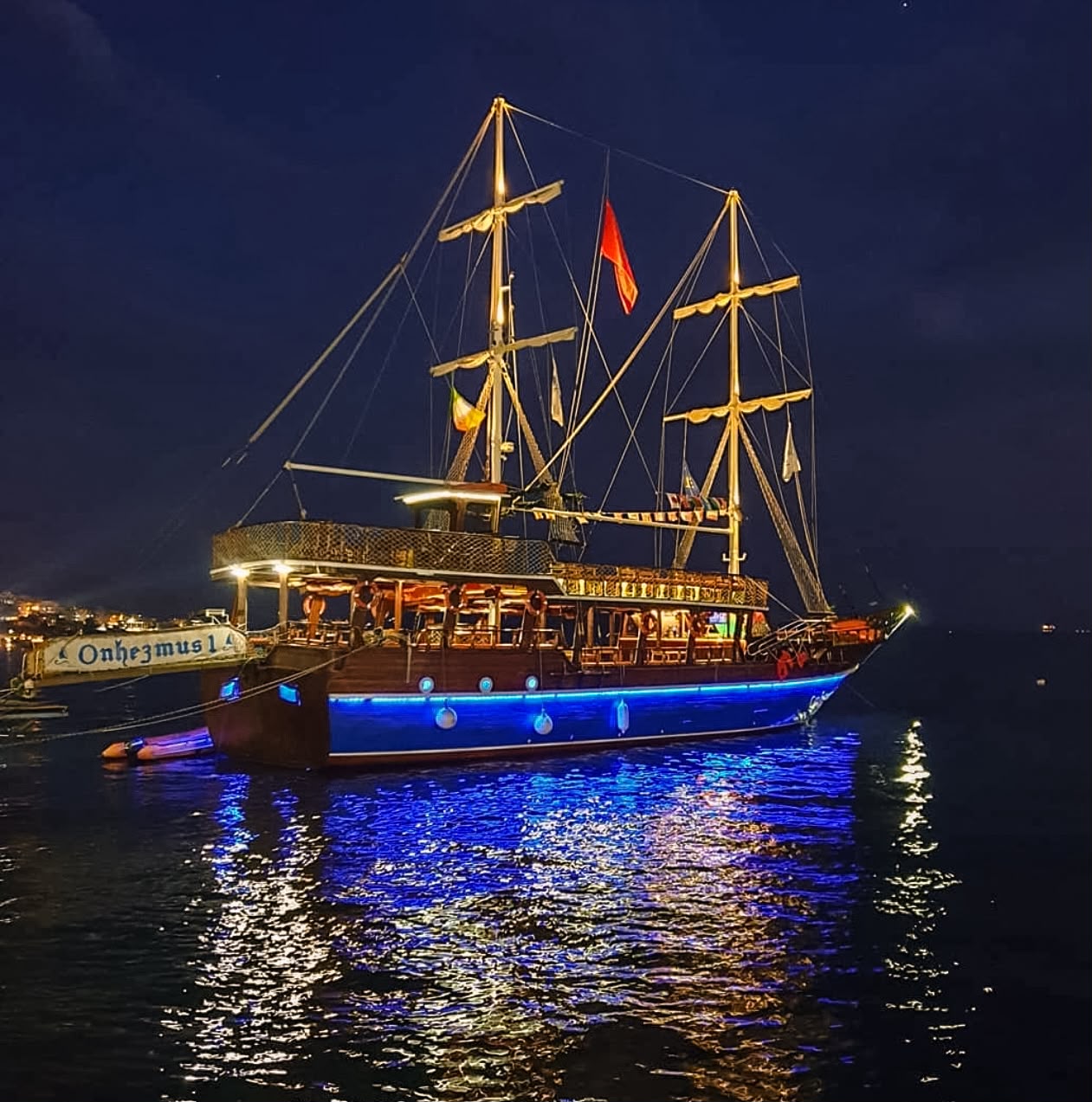 tour boat docked in Sarandë with multiple decks, comfortable seating, and the Ionian Sea in the background. The vessel is ready for sightseeing and day trips along the Albanian Riviera.