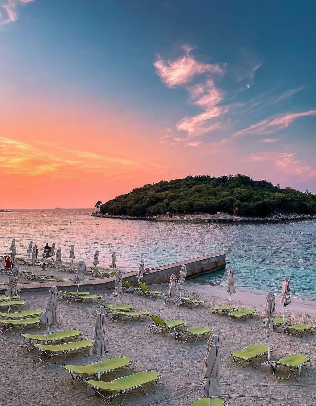 Golden sunset over Ksamil with warm orange and pink tones reflecting across the calm sea and silhouetted islands in the distance. A peaceful end to the day that captures the beauty of 2 Days in Ksamil.
