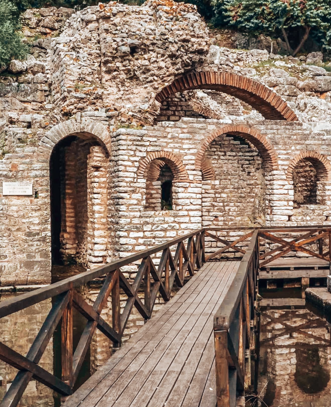 Close view of historic ruins in Butrint National Park with stone construction and partially preserved architectural elements. The remains suggest an old settlement with layered history and cultural significance.