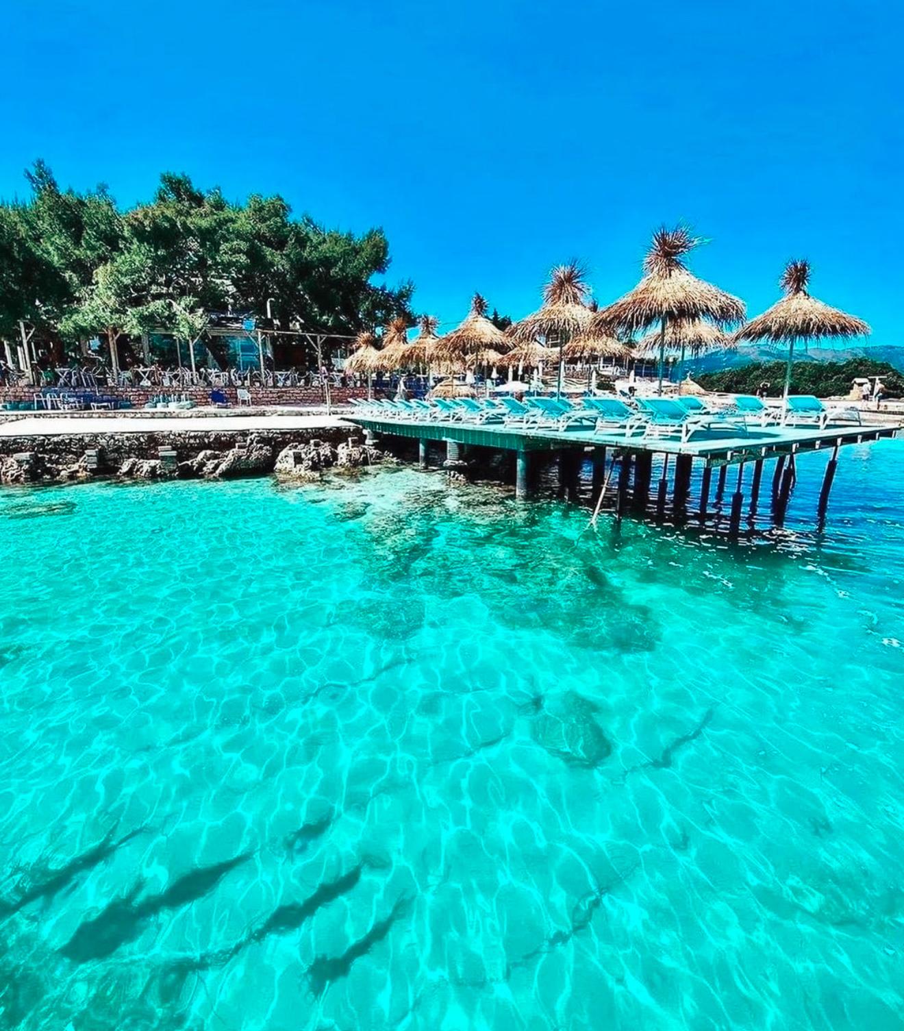 Wooden platforms with sunbeds extend over the clear turquoise sea in Ksamil, offering a relaxing place to sunbathe just above the water. These seaside platforms are a popular way to unwind during 2 Days in Ksamil while enjoying the coastal views.