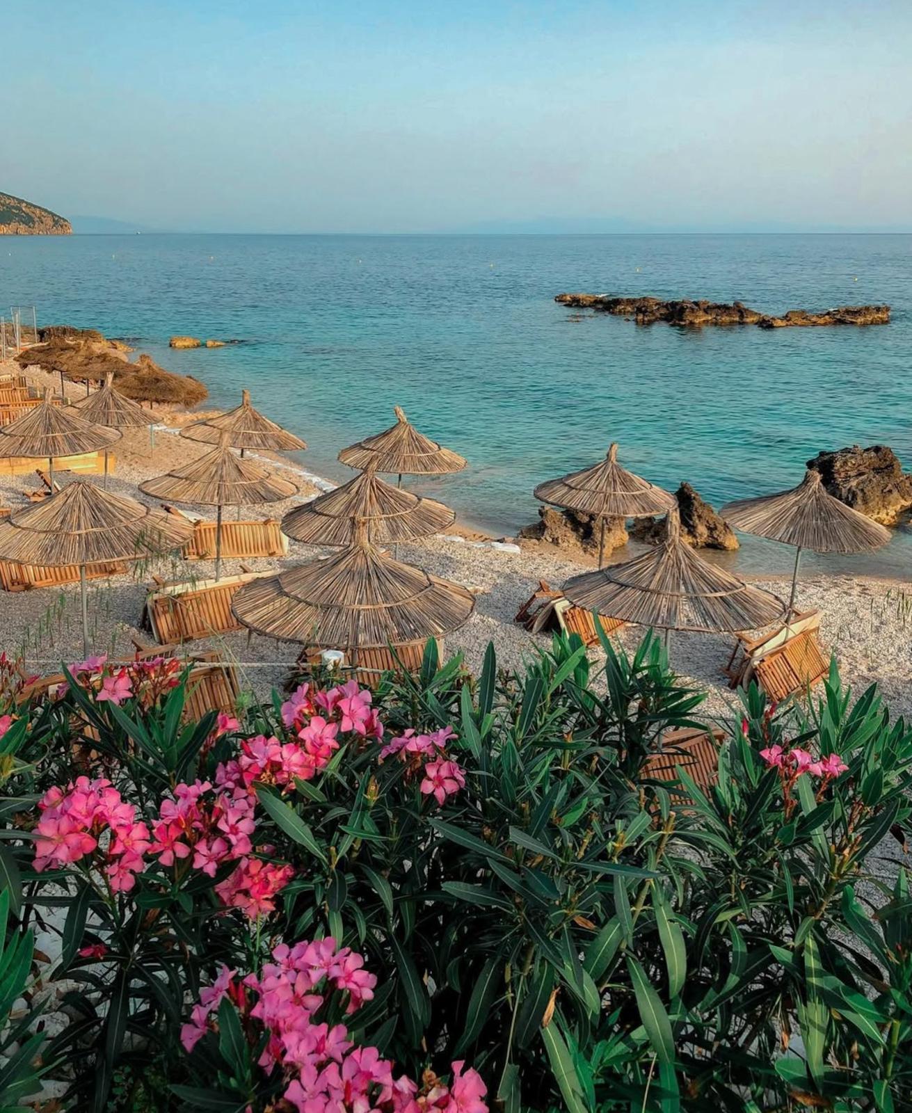 View of Ksamil Beach from a nearby street with turquoise water, beach umbrellas, and the small islands visible in the distance. This first glimpse of the coastline gives a sense of what to expect during 2 Days in Ksamil.