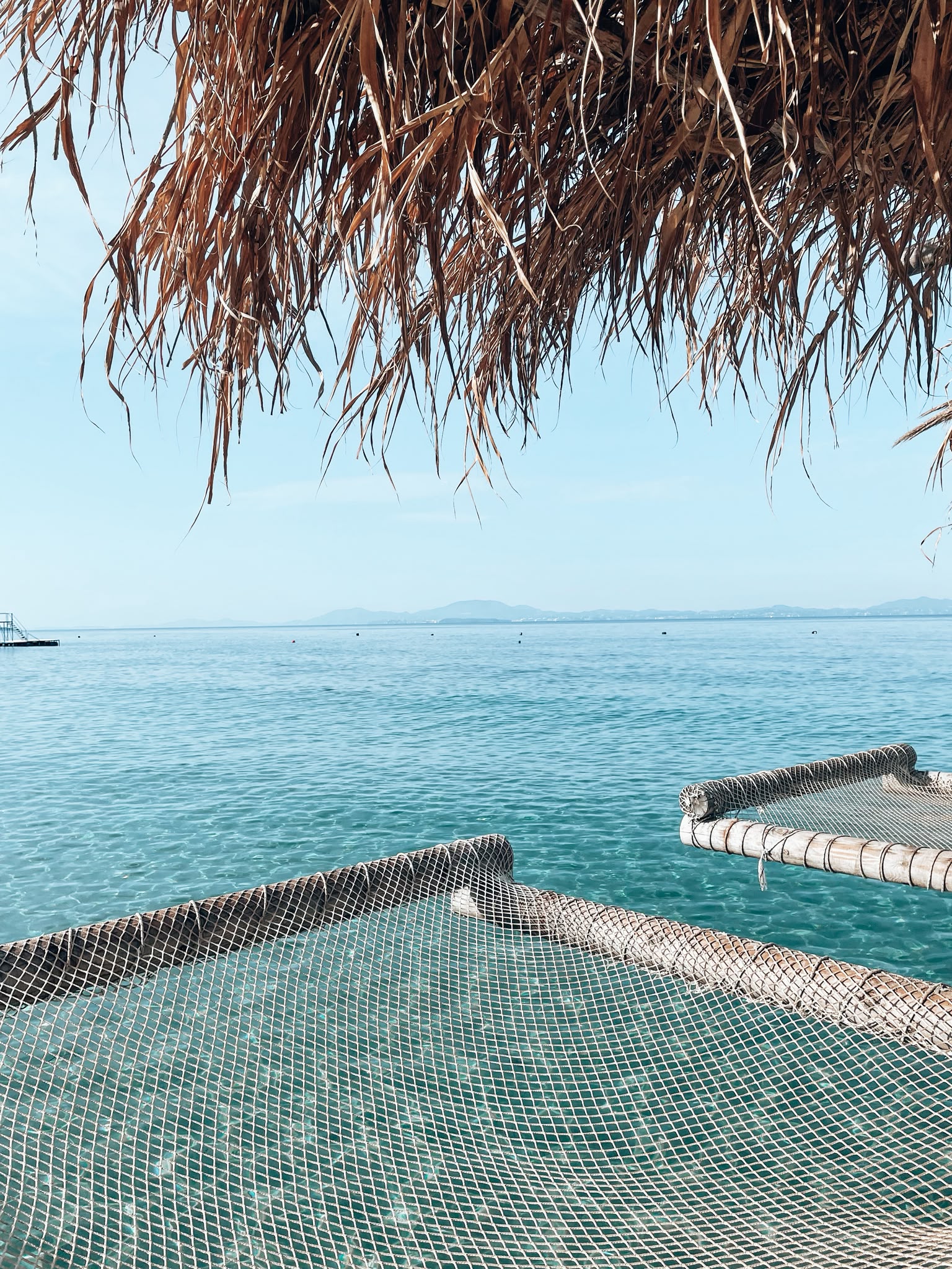 Sandy shoreline at Pema e Thatë Beach with clear turquoise water, gentle waves, and a peaceful coastal landscape. The secluded beach scenery shows the natural beauty of the Ksamil area.